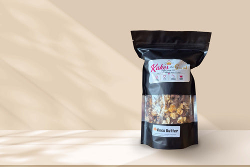 Kakes the Great Coco Butter kettle corn in a black resealable bag on a beige counter with a tan background. 